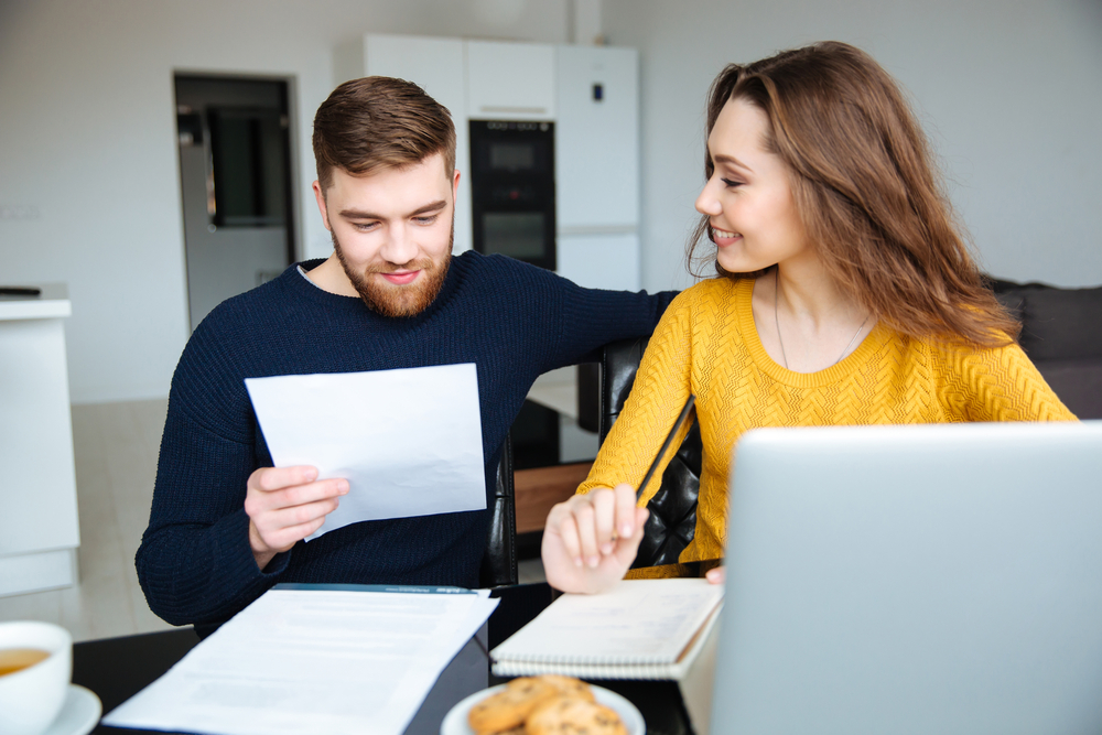 A couple reviewing their income, cash flow, and net worth on a laptop at home, representing financial education from Eternity Financial Alliance.
